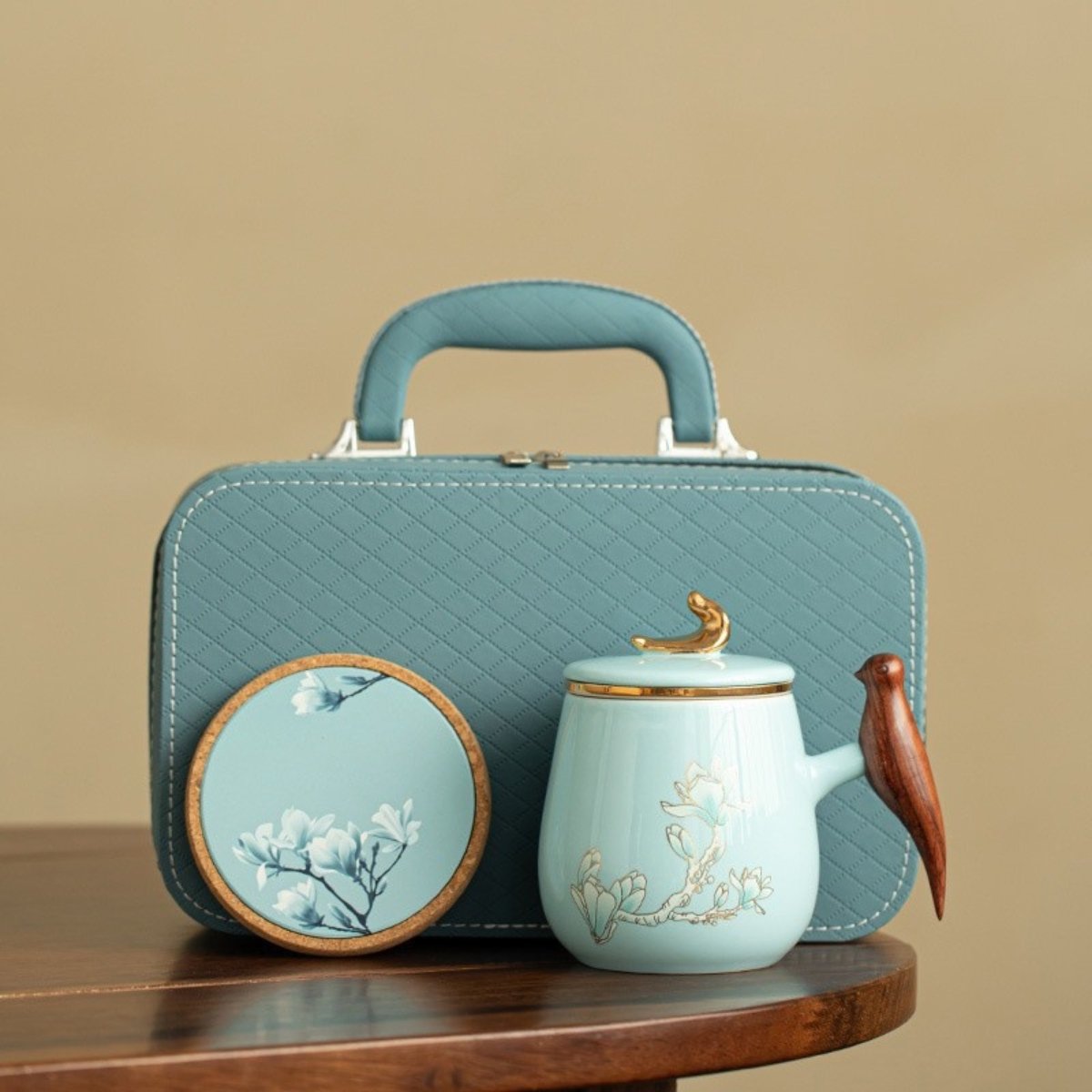 Ceramic tea infuser mug with magnolia design, blue glaze, lid, ergonomic handle, and protective storage pouch