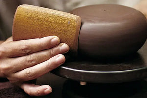 Smoothing the outer wall of the teapot with a bamboo tool